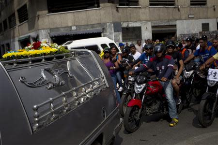 Relatives of a male gunshot victim ride on motorcycles as they follow the hearse, after forcing it to detour to their neighborhood as a tribute prior to burying their relative, in Caracas November 29, 2012. REUTERS/Carlos Garcia Rawlins