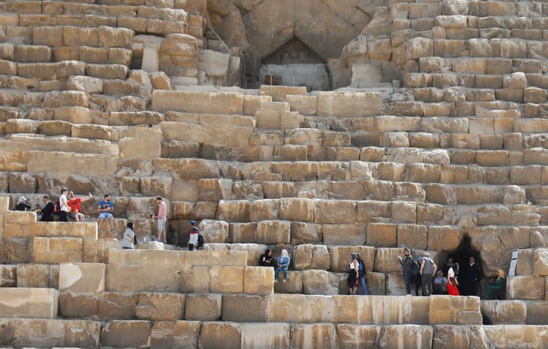 Egyptian police officers monitor and gurad as visitors climb the Great Pyramids of Giza, on the outskirts of Cairo