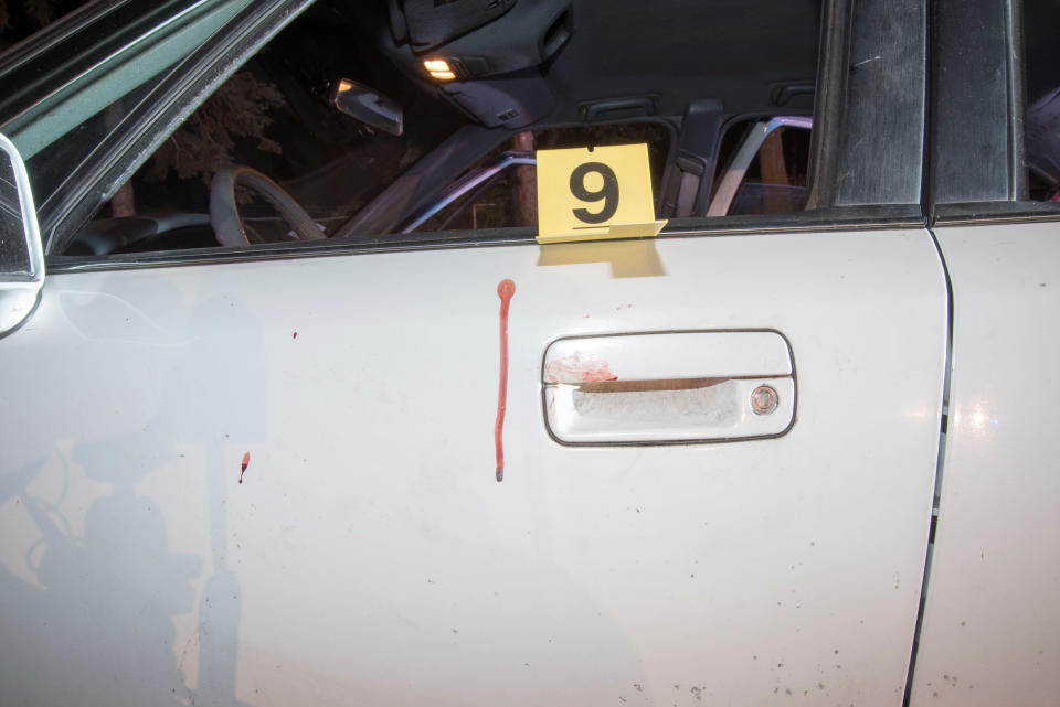 Bloodstains and a marker are seen on the car.&nbsp;