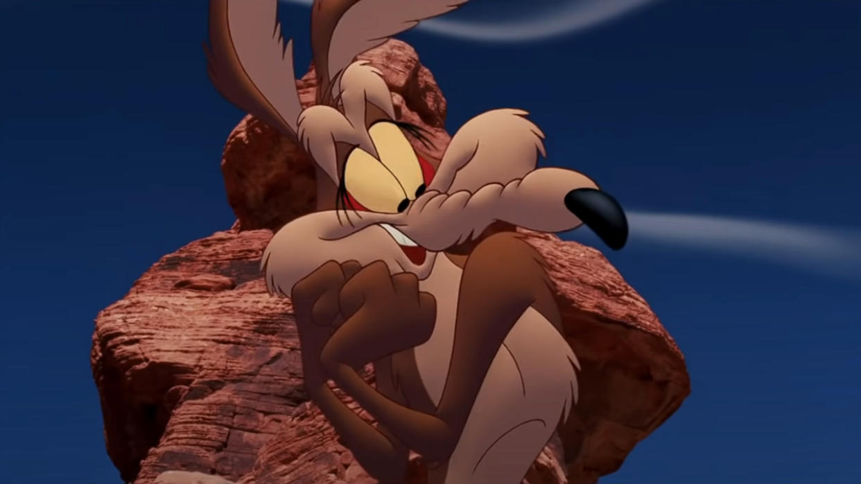  Wile E Coyote stands in front of a rock formation with a flattered expression in Looney Tunes: Back In Action. 