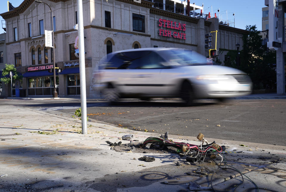 A car drives past the scene Monday, June 14, 2021, where police and witnesses say a woman was killed and multiple others were injured when an SUV struck a parked car and tossed it into demonstrators during a protest late Sunday in Uptown Minneapolis. (David Joles/Star Tribune via AP)