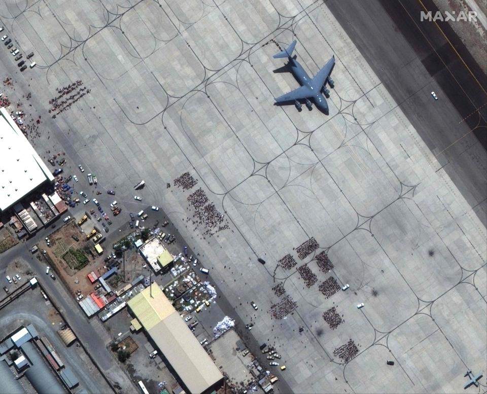 This handout satellite image released by Maxar Technologies shows crowds of people waiting on the tarmac at Kabul's Hamid Karzai International Airport in Afghanistan, with a C-17 transport aircraft ready, on Aug. 23, 2021.