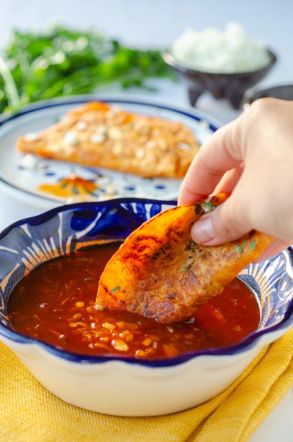 A vegan birria taco being dipped in broth.