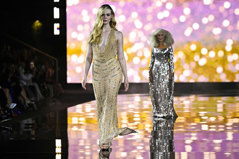 Dos potencias en escena. Elle Fanning lidera la pasarela con un vestido de noche dorado semitransparente mientras que Helen Mirren la sigue con un modelo en plateado 