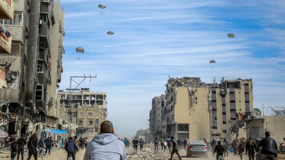 PHOTO: Palestinians run along a street as humanitarian aid is airdropped in Gaza City on March 1, 2024, amid the ongoing conflict between Israel and the Hamas militant group. (AFP via Getty Images)