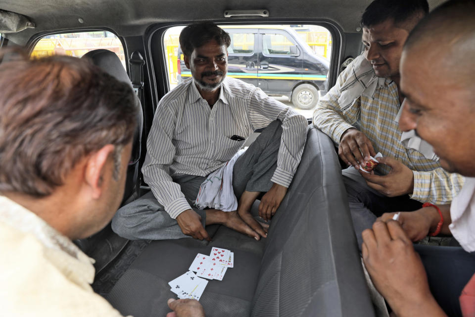 Taxi drivers play cards during a public transport strike in New Delhi, India, Thursday, Sept. 19, 2019. Commuters in the Indian capital are facing problems as a large section of the public transport, including private buses, auto-rickshaws and a section of app-based cabs Thursday remained off the roads in protest against a sharp increase in traffic fines imposed by the government under a new law.(AP Photo/Manish Swarup)