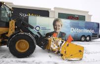 A snow blower passes Parti Quebecois Pauline Marois bus during a campaign stop in Laval, Quebec March 30, 2014. Quebec voters will go to the polls in a provincial election April 7. REUTERS/Christinne Muschi (CANADA - Tags: ELECTIONS POLITICS)