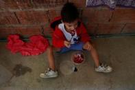 Luis Berrios sits on the floor as he eats his meal at his hovel in Caracas, Venezuela June 26, 2017. Picture taken June 26, 2017. REUTERS/Marco Bello