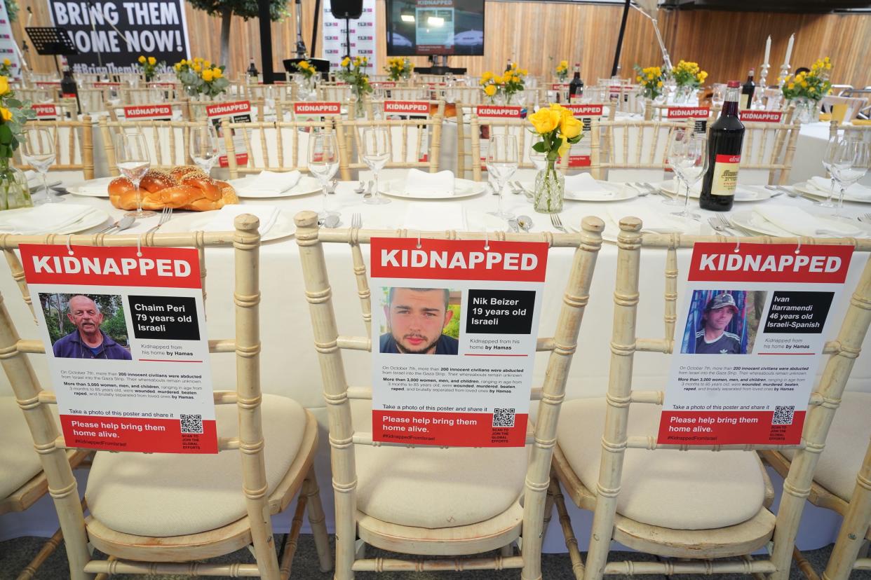 The Empty Shabbat Table installation in London, showing kidnapped posters of three missing Israeli men (PA)