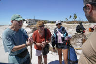 Residents Jim Delaney, left, and Judy Hicks, center, speak with Project DYNAMO rescue personel before being transported to Fort Myers, after Hurricane Ian moved through, Friday, Sept. 30, 2022, on Sanibel Island, Fla. (AP Photo/Steve Helber)