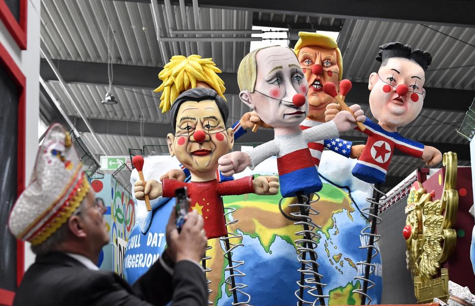 A satiric carnival float depicting the leaders of China, United Kingdom, Russia, USA and North Korea, Xi Jinping, Boris Johnson, Vladimir Putin, Donald Trump and Kim Jong-un as puppets is watched by a reveller during a preview in a hall in Cologne, Germany, Tuesday, Feb. 18, 2020. The traditional carnival parades on Rosemonday make fun of politics and are watched by hundreds of thousands in the streets of Cologne, Duesseldorf and Mainz. (AP Photo/Martin Meissner)