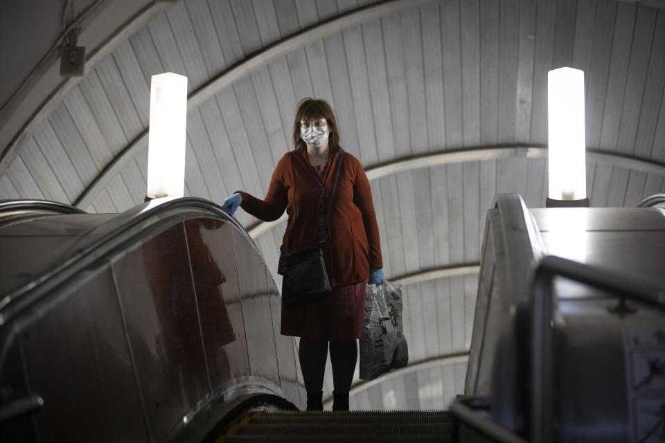 A woman wearing face mask and gloves to protect against coronavirus, observes social distancing guidelines as she travels on the escalator up from the subway in Moscow, Russia, Tuesday, May 12, 2020. From Tuesday onward, wearing face masks and latex gloves is mandatory for people using Moscow's public transport. President Vladimir Putin on Monday declared an end to a partial economic shutdown across Russia due to the coronavirus pandemic, but he said that many restrictions will remain in place. (AP Photo/Alexander Zemlianichenko)