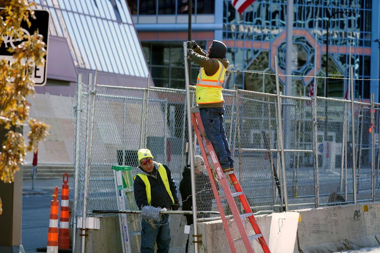 Workers install barbed wire on fencing outside the Hennepin County Government Center, Wednesday, Feb. 23, 2021 in Minneapolis, as part of security preparation for the trial of former Minneapolis police officer Derek Chauvin. The trial is slated begin with jury selection on March 8. Chauvin is charged with murder the death of George Floyd during an arrest last May in Minneapolis. (AP Photo/Jim Mone) (AP)