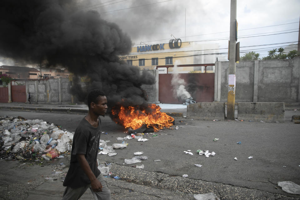 A man walks past a burning barricade during a protest in Port-au-Prince, Haiti, Monday, Aug. 22, 2022. Protesters marched through Haiti's capital and other major cities, blocking roads and shutting down businesses to demand that Prime Minister Ariel Henry step down and call for a better quality of life. (AP Photo/Odelyn Joseph)