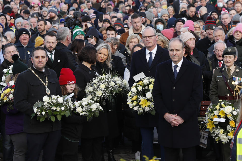The Irish Prime Minister Micheal Martin, second right , pays his respects as people take part in a march to commemorate the 50th anniversary of the 'Bloody Sunday' shootings with the front rank holding photographs of some of the victims in Londonderry, Sunday, Jan. 30, 2022. In 1972 British soldiers shot 28 unarmed civilians at a civil rights march, killing 13 on what is known as Bloody Sunday or the Bogside Massacre. Sunday marks the 50th anniversary of the shootings in the Bogside area of Londonderry .(AP Photo/Peter Morrison)