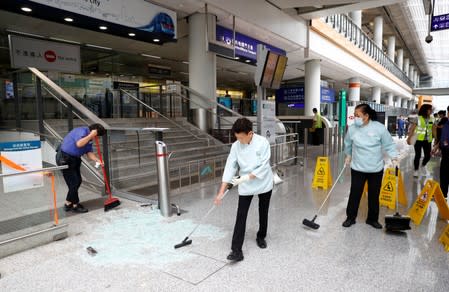 Staff clean up glass from a glass door broken by protesters inside Hong Kong International Airport, Hong Kong, China