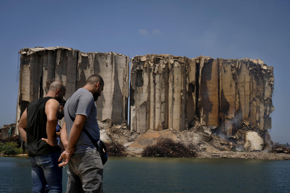 Journalists look at grain silos, that were severely damaged in the massive Beirut Port blast in August 2020, in Beirut, Lebanon, Thursday, July 14, 2022. Lebanese caretaker Economy Minister Amin Salam said Thursday that the capital's port silos, shredded in a massive blast two years ago may collapse, as authorities struggle to contain a fire. (AP Photo/Bilal Hussein)