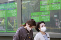 People walk by an electronic stock board of a securities firm in Tokyo, Wednesday, April 21, 2021. Shares skidded in Asia on Wednesday after Wall Street closed lower for a second straight day, led by drops in technology companies and banks. (AP Photo/Koji Sasahara)