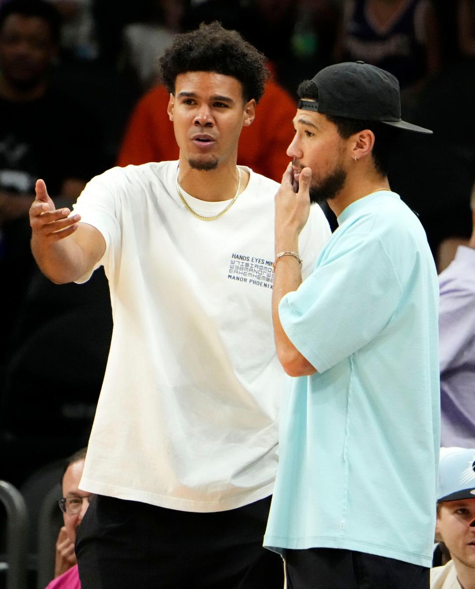 Former Phoenix Suns Cam Johnson talks to Devin Booker during the Phoenix Mercury game at Footprint Center in Phoenix on June 21, 2023.