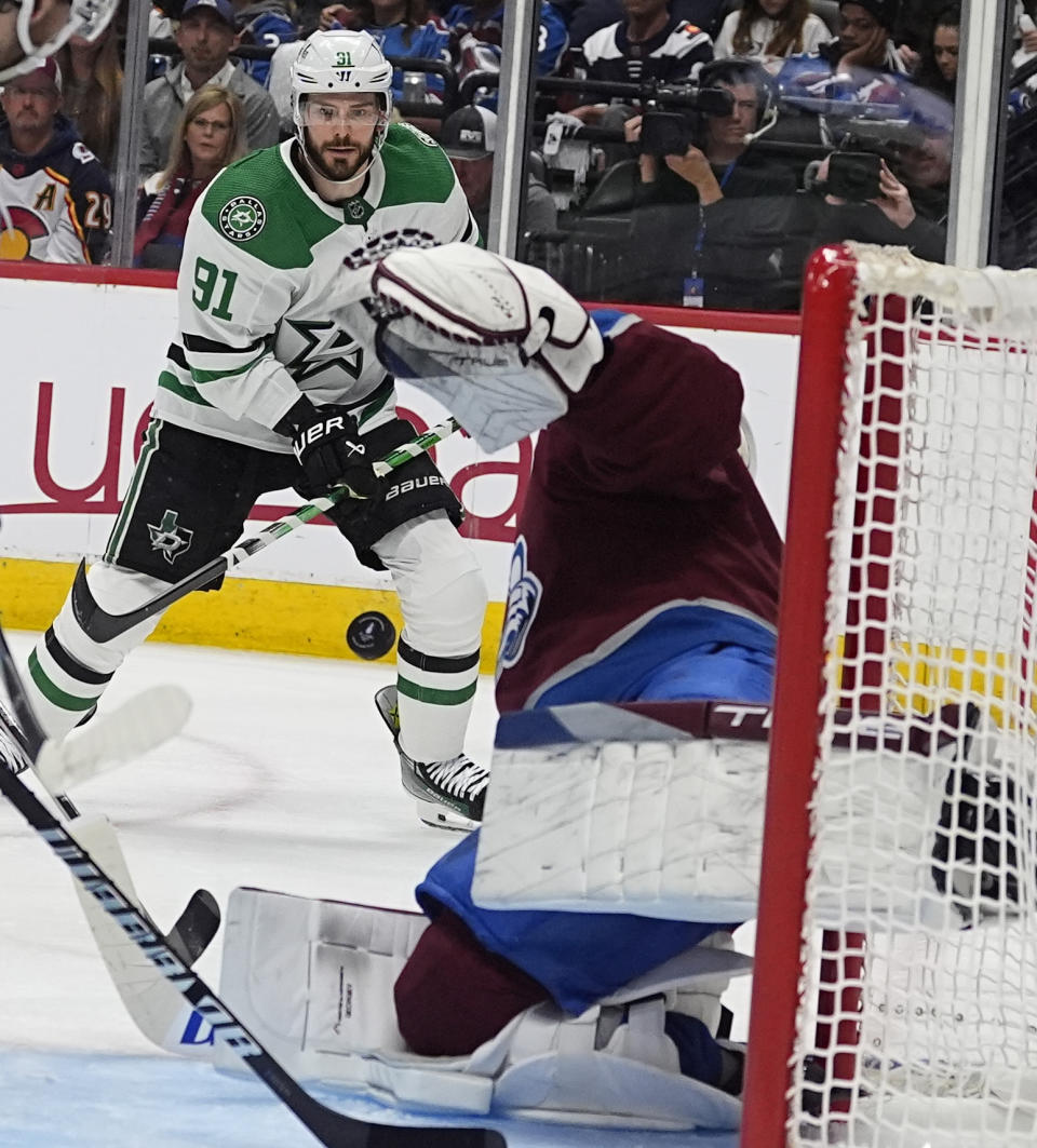 Dallas Stars center Tyler Seguin, back, shoots the puck toward Colorado Avalanche goaltender Alexandar Georgiev during the second period of Game 3 of an NHL hockey Stanley Cup playoff series Saturday, May 11, 2024, in Denver. (AP Photo/David Zalubowski)