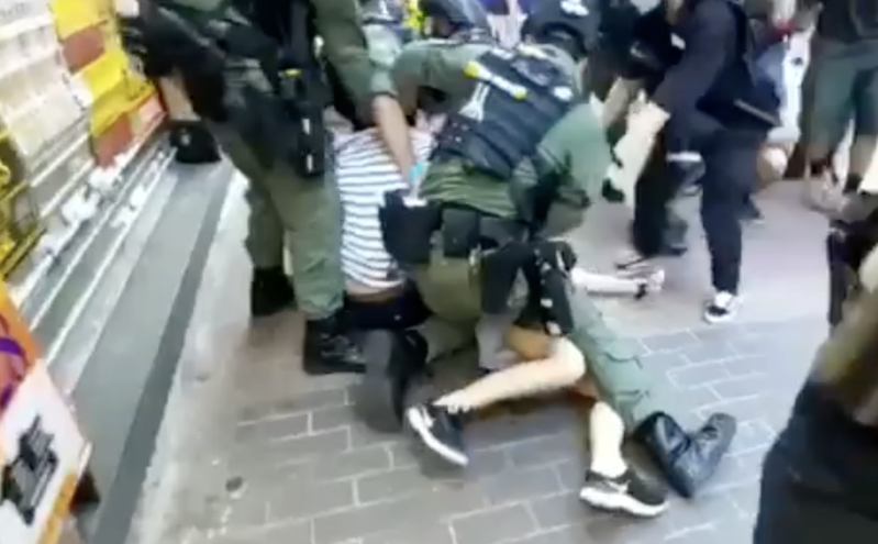 「906」九龍大遊行中，一名12歲女孩和家人上街購物，剛好經過遊行現場，竟被港警「騎身」壓倒在地。（翻攝科大電台新聞組影片）