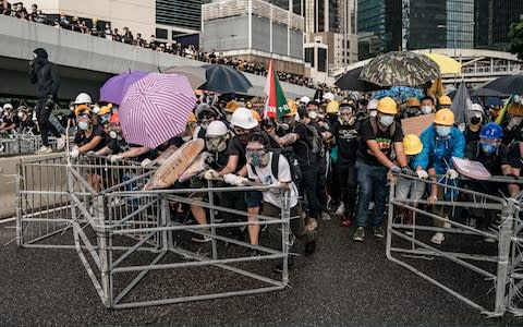  Anti-extradition protesters push barricades toward police on a street during a stand-off outside the Legislative Council Complex - Credit: Getty