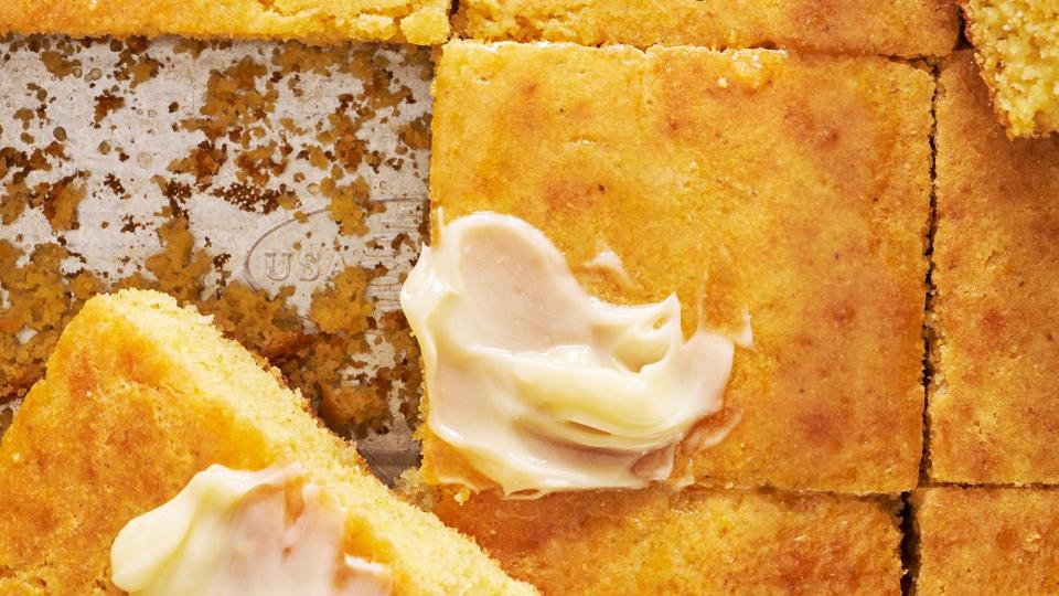 pan of homemade cornbread sliced into squares and topped with honey butter