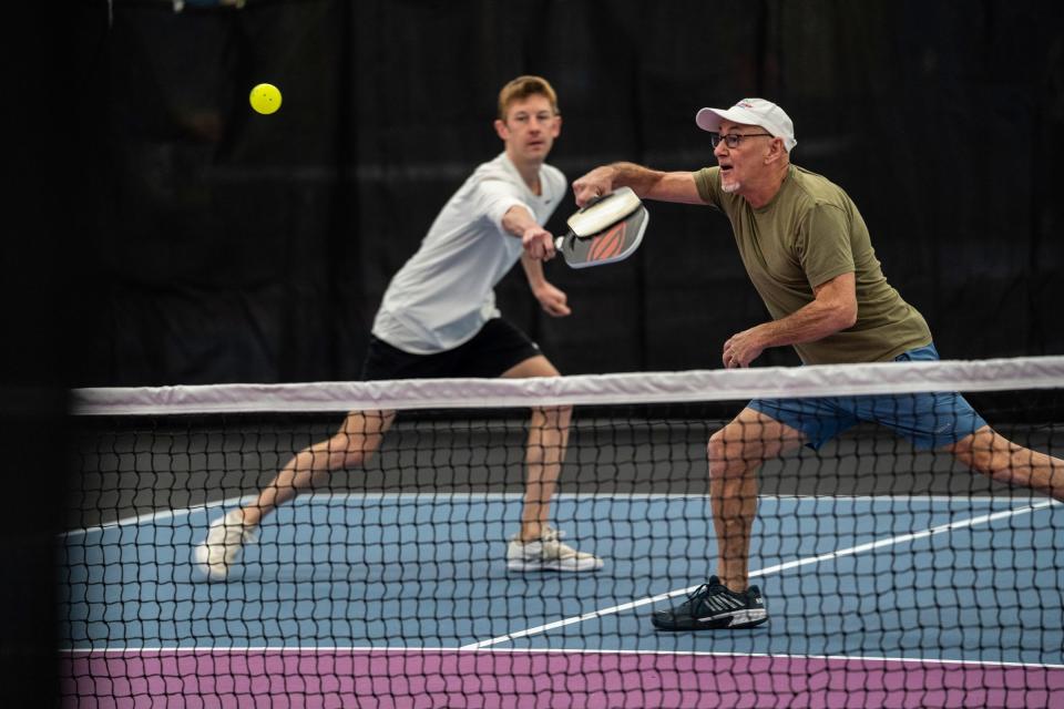 Mike Katona, right, of Chelsea returns a ball during a match for the opening for the privately owned Wolverine Pickleball in Scio Township on Friday, December 1, 2023. The new, $7 million 39,000-square-foot indoor-outdoor facility will be the state's largest.