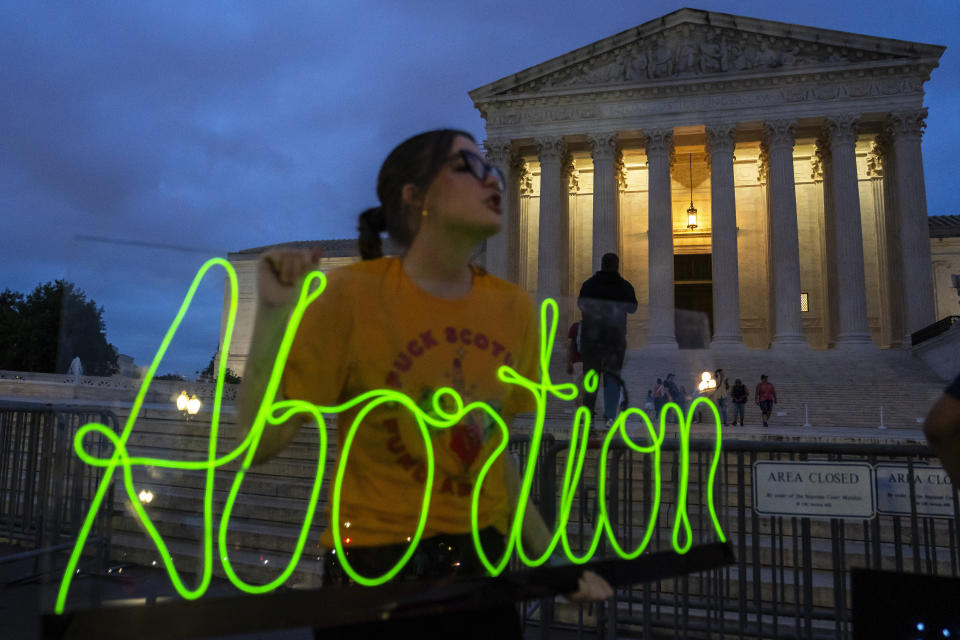 Hope Neyer marks the first anniversary of the Supreme Court's decision in Dobbs v. Jackson Women's Health Organization, the case widely considered to have overturned Roe v. Wade, by displaying a neon sign in support of abortion access in front of the Supreme Court on Friday, June 23, 2023, Washington. (AP Photo/Nathan Howard)