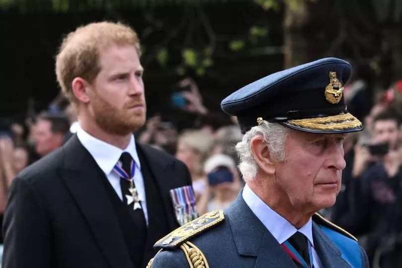 King Charles III and Britain's Prince Harry, Duke of Sussex walk behind the coffin of Queen Elizabeth II