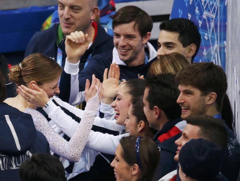 Carolina Kostner of Italy is greeted by her teammates in the "kiss and cry" area during the Team Ladies Short Program at the Sochi 2014 Winter Olympics