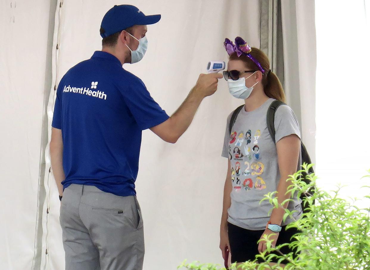 A guests gets her temperature taken before entering the official reopening day of the Magic Kingdom at Walt Disney World in Lake Buena Vista, Fla., on Saturday, July 11, 2020.