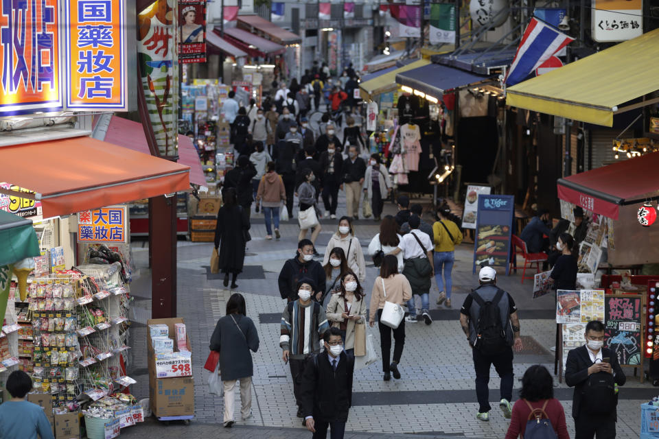 People wearing face masks walk through a shopping street in Tokyo on Thursday, Nov. 19, 2020. Japan's number of reported coronavirus infections hit a record high Thursday, and the prime minister urged maximum caution but stopped short of calling for restrictions on travel or business. (AP Photo/Hiro Komae)