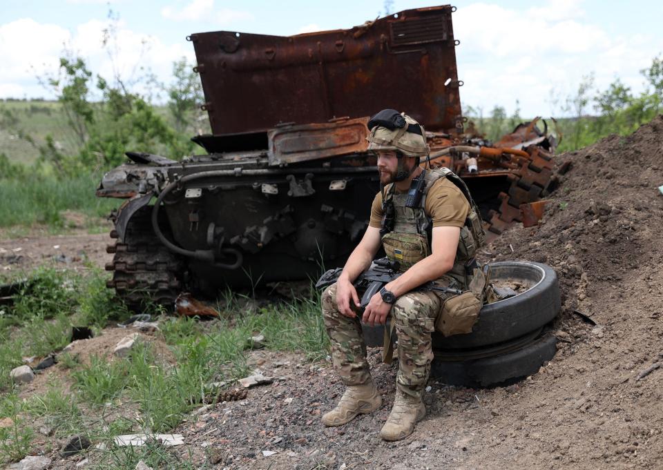 A Ukrainian serviceman sits next to a destroyed Russian tank at an abandonned Russian position near the village of Bilogorivka not far from Lysychansk, Lugansk region, on June 17, 2022, amid the Russian invasion of Ukraine.