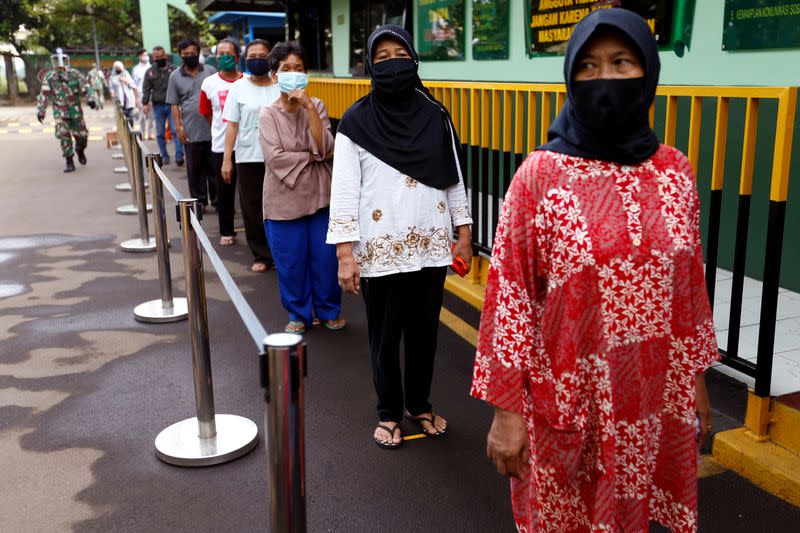 FILE PHOTO: People wearing protective face mask practice social distancing while receiving rice from an automated rice ATM distributor amid the spread of the coronavirus disease (COVID-19) in Jakarta