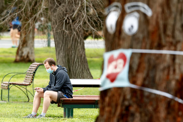 A man is seen sitting on a bench and looking at his phone at Melbourne's Albert Park. Source: Getty Images