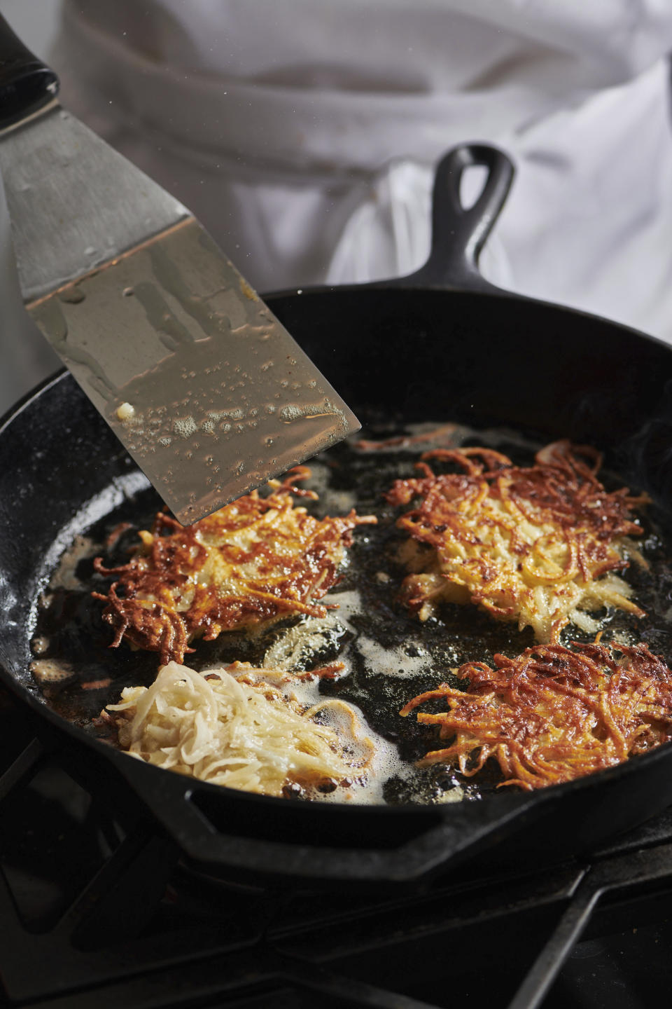 Potato pancakes, or latkes, are prepared in New York in August 2020. Latkes are the food most traditionally associated with Hanukkah. There are all kinds of modern variations using other vegetables and other toppings. (Cheyenne M. Cohen via AP)