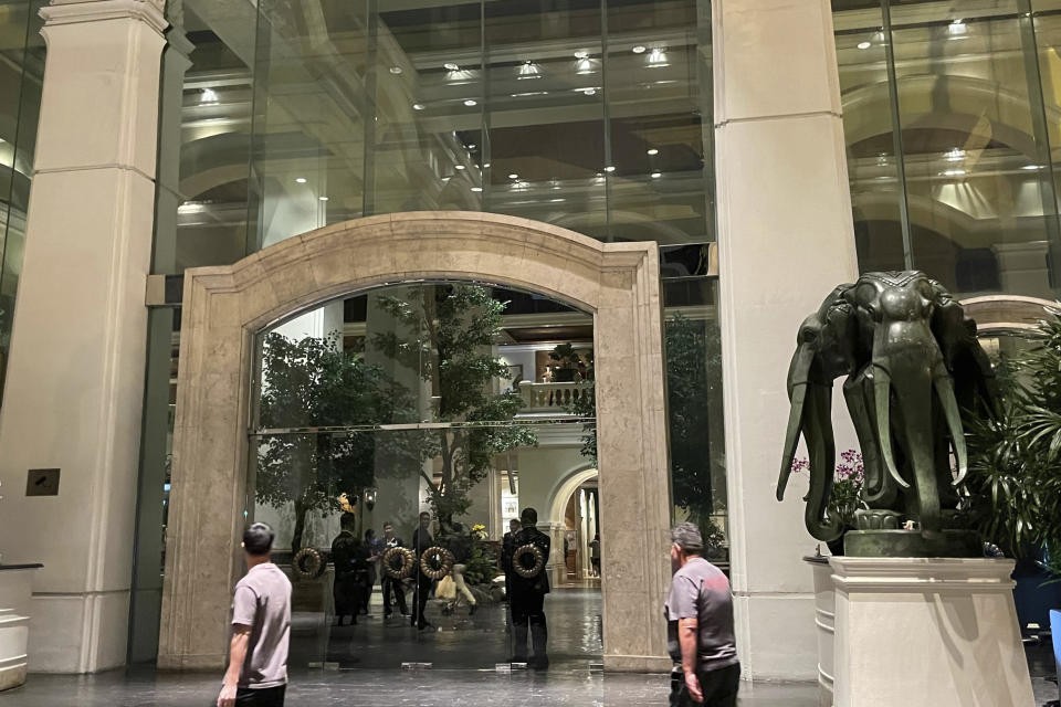 Staff stand in the lobby of a hotel where a number of people were found dead in Bangkok, Thailand, Tuesday, July 16, 2024. (AP Photo/Napat Kongsawad)