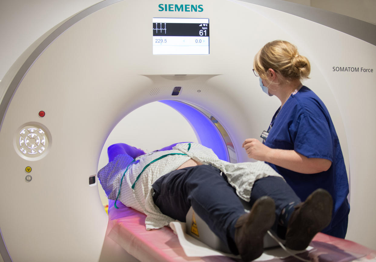 A patient undergoing a CT scan with a nurse beside them