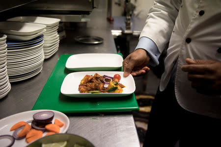 Abdul Ahad, owner of the City Spice curry house, serves a vegan meal in the kitchen of his restaurant on Brick Lane in London, Britain January 7, 2019. Picture taken January 7, 2019. REUTERS/Simon Dawson