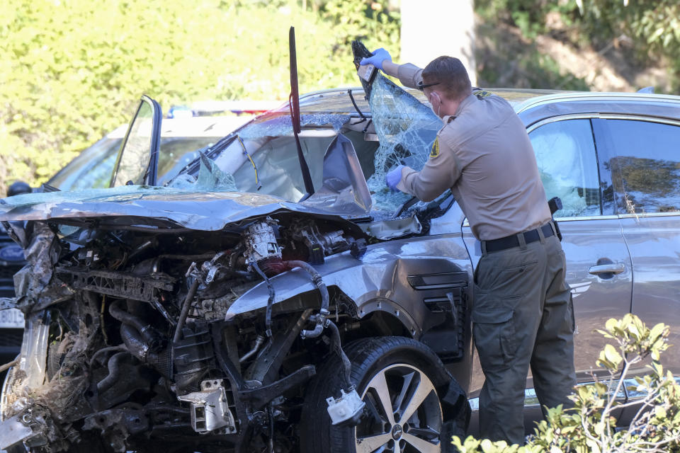 FILE - In this Feb. 23, 2021, file photo, a law enforcement officer looks over a damaged vehicle following a rollover accident involving golfer Tiger Woods in the Rancho Palos Verdes suburb of Los Angeles. A man who found Woods unconscious in a mangled SUV last week after the golf star who later told sheriff's deputies he did not know how the collision occurred and didn't even remember driving, crashed the vehicle in Southern California, authorities said in court documents. Law enforcement has not previously disclosed that Woods had been unconscious following the collision. (AP Photo/Ringo H.W. Chiu,File)