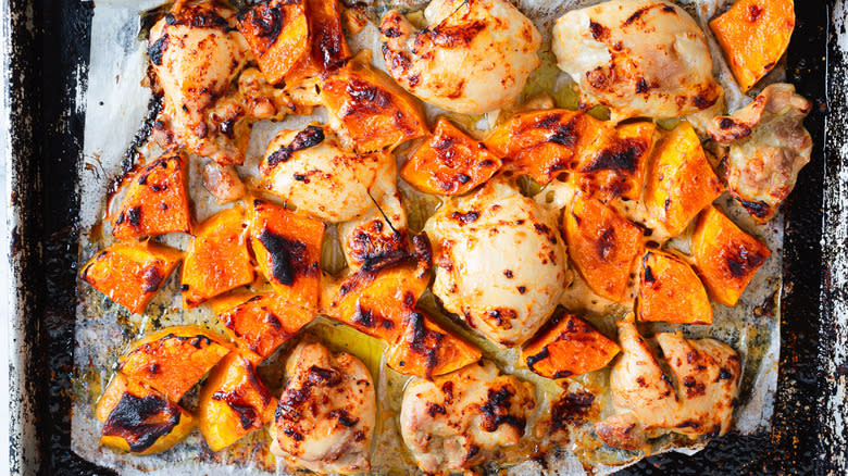 Baked chicken and squash on baking sheet