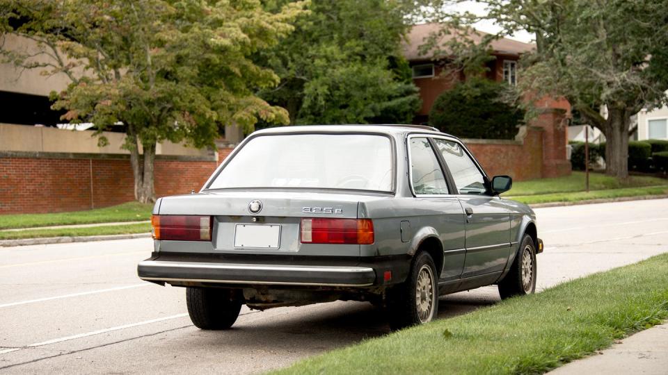 a gray bmw 3 series two door car parked on the side of a road