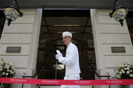 An employee stands in front of the entrance of the Peninsula Paris luxury hotel during its official opening ceremony in Paris August 1, 2014. REUTERS/Christian Hartmann