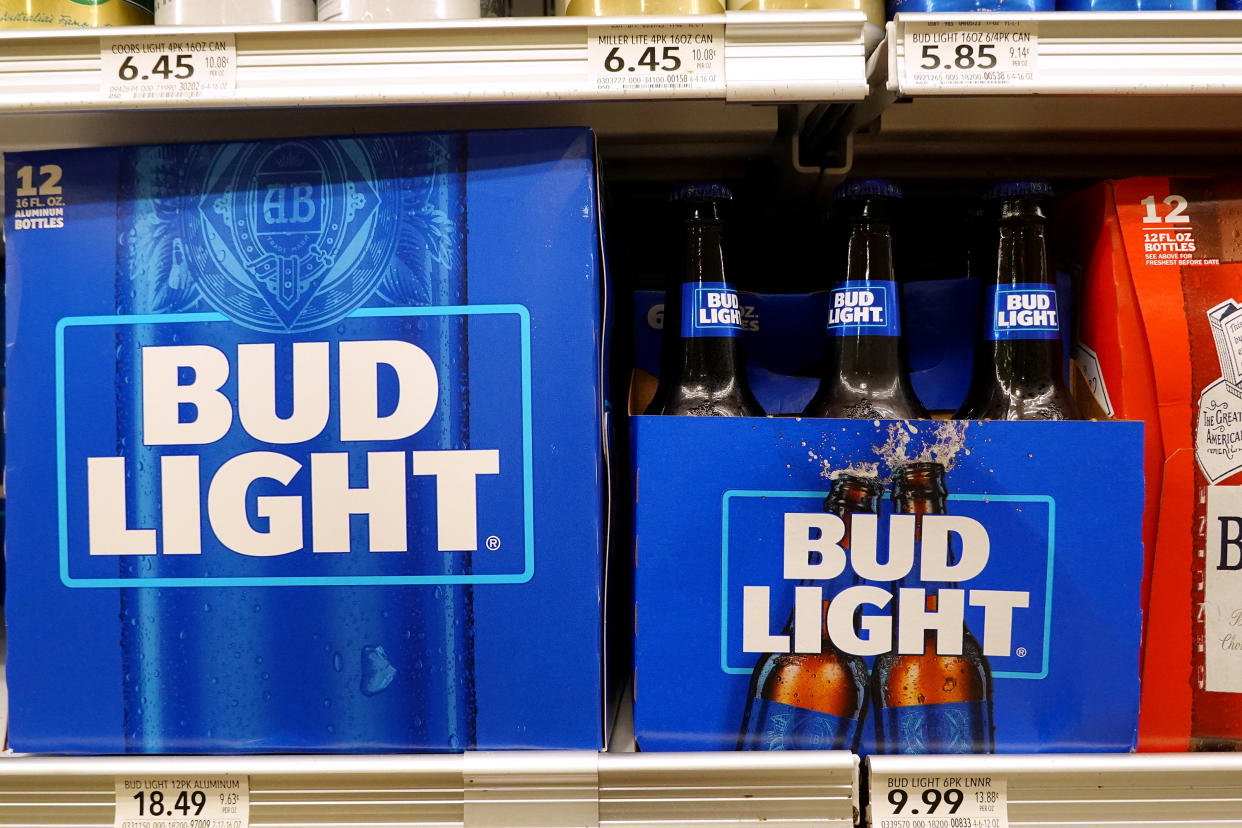 A six-pack and 12-pack of Bud Light beer sit on a shelf.