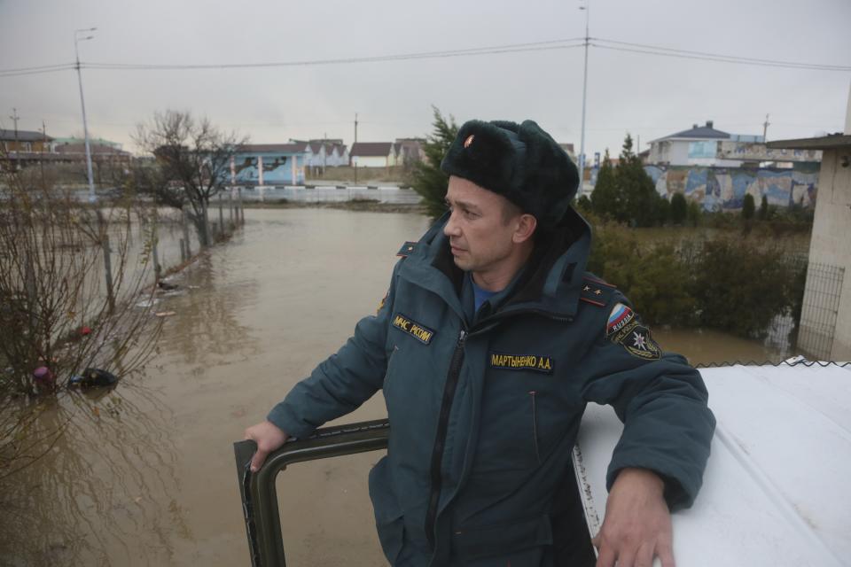 An Emergency Situation Ministry employee looks at a flooded area after a storm near Evpatoria in Crimea, Monday, Nov. 27, 2023. A storm in the Black Sea took down power grids and left almost half a million people without power after it flooded roads, ripped up trees and damaged buildings in Crimea, Russian state news agency Tass said. (AP Photo)