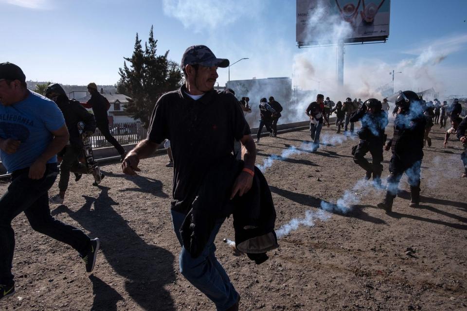 <p>Central American migrants -mostly Hondurans- run along the Tijuana River near the El Chaparral border crossing in Tijuana, Baja California State, Mexico, near US-Mexico border, after the US border patrol threw tear gas from the distance to disperse them after an alleged verbal dispute, on November 25, 2018.</p>