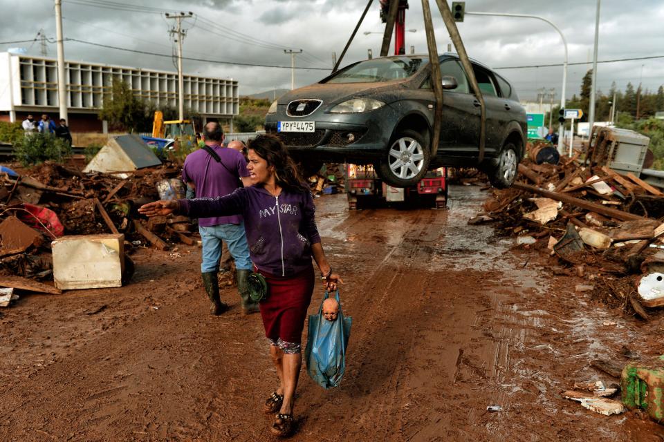 <p>A woman gestures as a car is removed from the road in the town of Mandra, northwest of Athens, on Nov. 15, 2017, after heavy overnight rainfall in the area caused damage and left seven people dead. (Photo: Valerie Gache/AFP/Getty Images) </p>