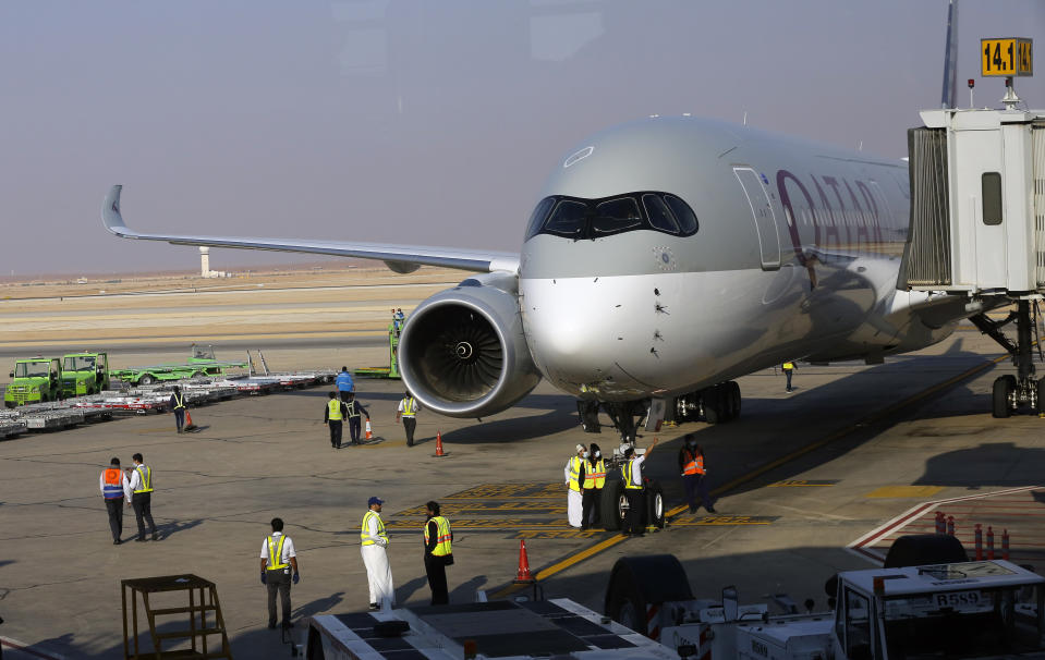 Saudi airport officials surround the first Qatar Airways plane in three years to land at King Khalid Airport in Riyadh, Saudi Arabia, Monday, Jan. 11, 2021. Saudi Arabia, along with the UAE, Bahrain and Egypt, ended a three-year dispute with Qatar following a Gulf Cooperation Council (GCC) summit in AlUla last week. (AP Photo/Amr Nabil)