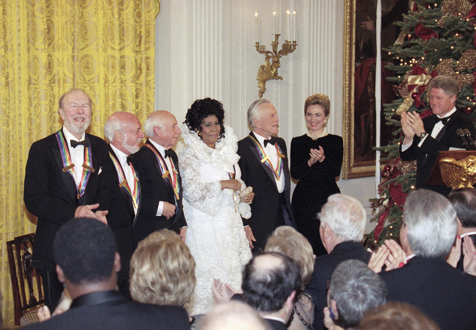 FILE - In this Dec. 4, 1994 file photo, President Bill Clinton, from right, and first lady Hillary Rodham Clinton applaud the 1994 Kennedy Center Honors award recipients, from left, songwriter Pete Seeger, director Harold Prince, composer Morton Gould, singer Aretha Franklin and actor Kirk Douglas during a reception in the East Room of the White House. Franklin died Thursday, Aug. 16, 2018 at her home in Detroit. She was 76. (AP Photo/Doug Mills, File)